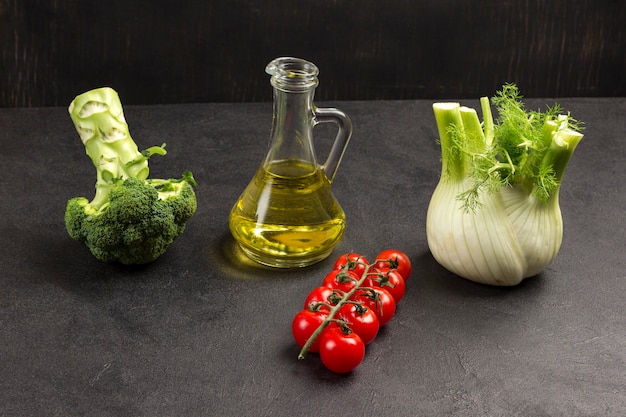 Pomodorini, broccoli, finocchi e bottiglia di vetro con olio.