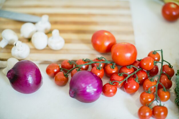 Pomodorini, cipolle e funghi sul piano di lavoro della cucina