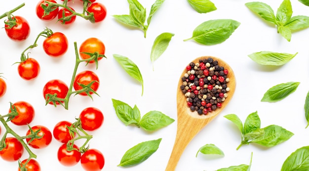 Pomodorini freschi con foglie di basilico e diversi tipi di grani di pepe