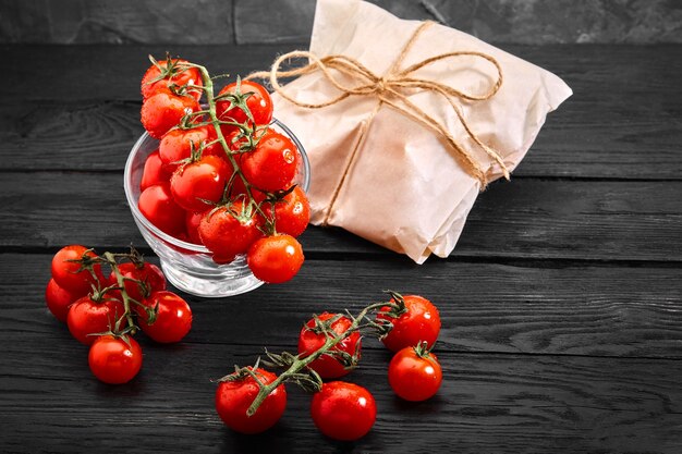 Pomodorini freschi organici su uno sfondo scuro, consegna di cibo. Copia spazio.