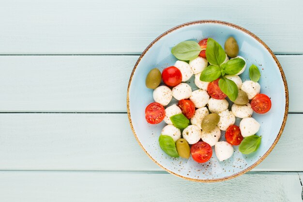 Pomodorini, mozzarella, basilico e spezie sulla lavagna di pietra grigia ardesia. Ingredienti dell'insalata caprese tradizionale italiana. Cucina mediterranea.