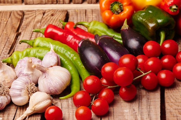 Pomodorini, peperoni, aglio, melanzane su un tavolo di legno. Verdure biologiche fresche.