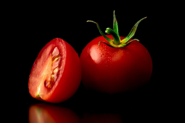 Pomodorini rossi lavati su fondo nero. Vista ravvicinata. Foto di concetto di mangiare sano