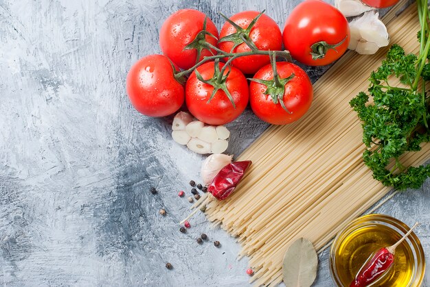 Pomodorini su un ramo, spaghetti, olio, prezzemolo e spezie