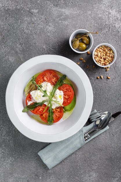 Pomodoro con ricotta in piatto bianco su fondo di cemento grigio