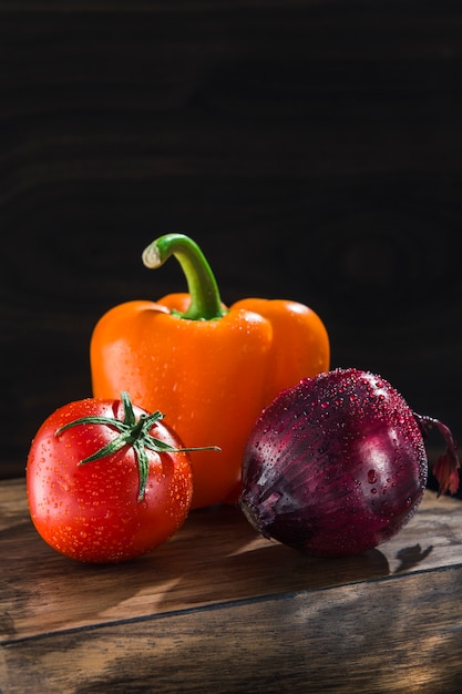 Pomodoro e peperoni della cipolla degli ortaggi freschi su un bordo di legno scuro