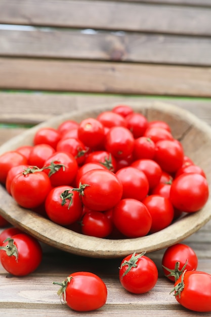 Pomodoro fresco raccolto in una ciotola di legno su uno sfondo