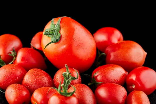 Pomodoro grande e pomodorini su una superficie nera