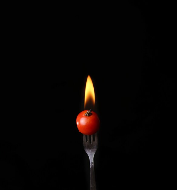 Pomodoro in fiamme con fiamme isolate su sfondo nero