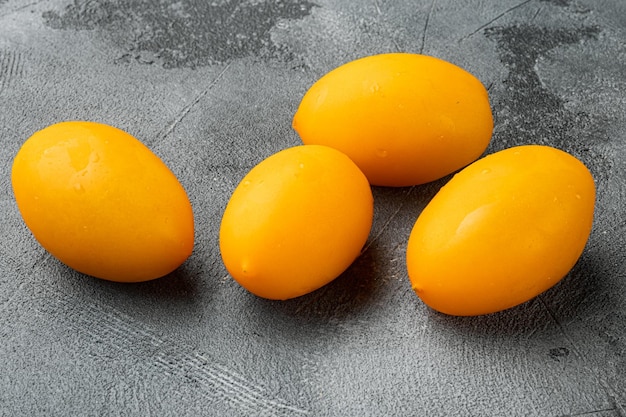 Pomodoro intero giallo con una fetta sul fondo grigio della tavola di pietra