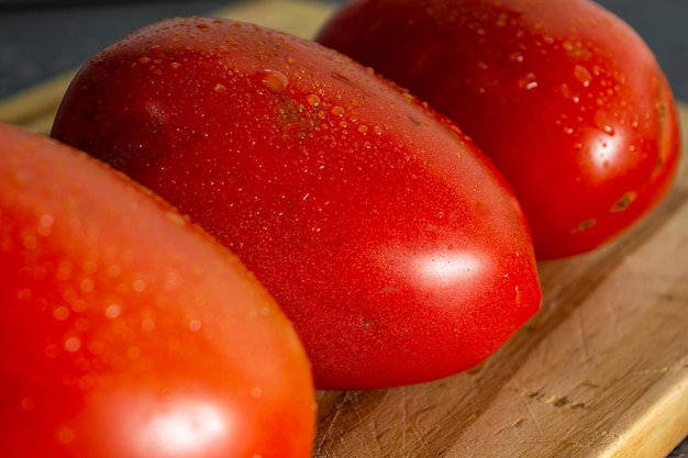 Pomodoro rosso con gocce d'acqua sul tagliere di legno