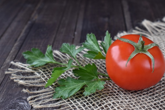 Pomodoro rosso con prezzemolo su uno sfondo di legno