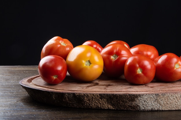 Pomodoro rosso maturo su legno con tavola nera.