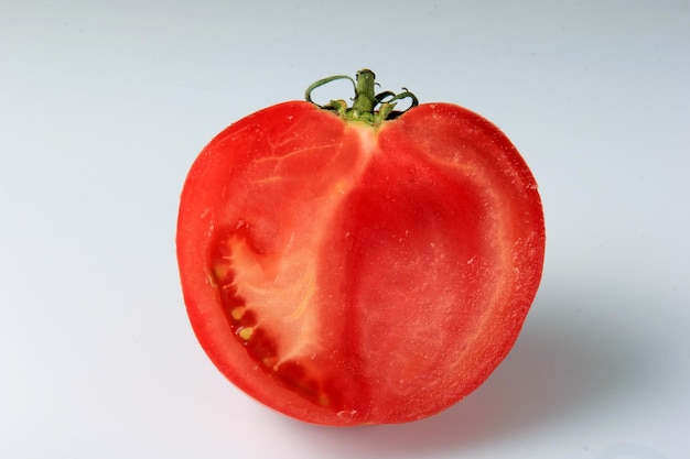 pomodoro rosso tagliato a metà su sfondo bianco. pomodoro maturo affettato