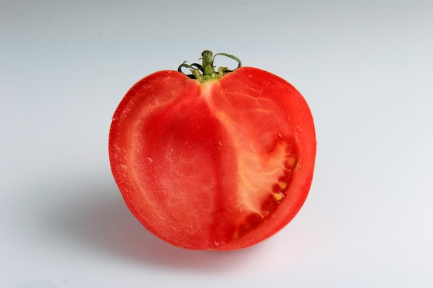 pomodoro rosso tagliato a metà su sfondo bianco. pomodoro maturo affettato