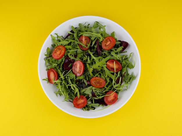 pomodoro sano e insalata di foglie mix su sfondo giallo