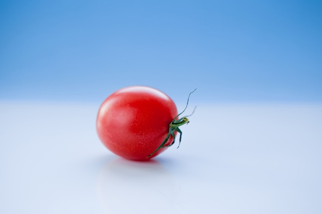 Pomodoro sugoso su una priorità bassa blu-chiaro, primo piano