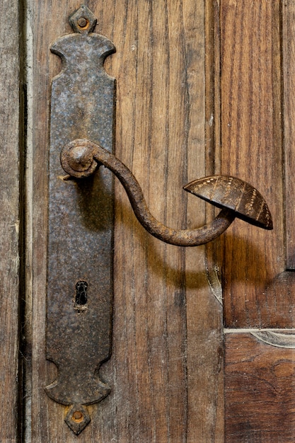 Pomolo e buco della serratura di una porta di metallo molto vecchi su una porta di legno rustica