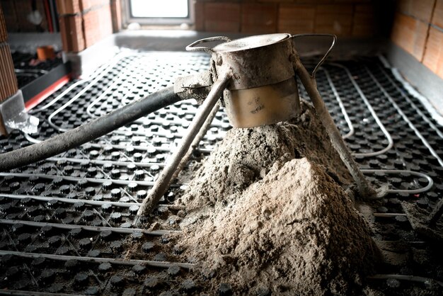 Pompa per calcestruzzo in azione uomo che lavora su massetto di superficie su tubi di riscaldamento a pavimento