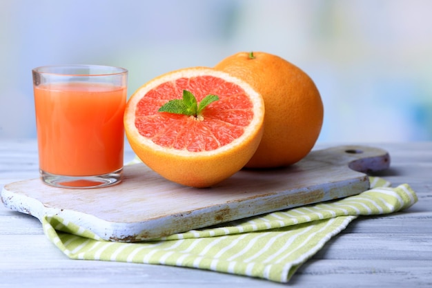 Pompelmi maturi e succo fresco sul tagliere su fondo di legno