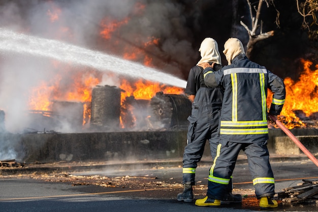 Pompiere che spruzza acqua dal grande tubo flessibile dell'acqua per prevenire incendi