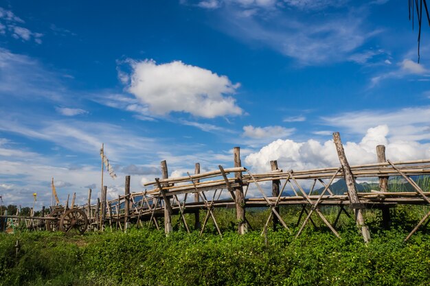 Ponte di legno accanto all&#39;azienda agricola verde a Nan, nordico della Tailandia, cielo blu, nuvola del cielo blu