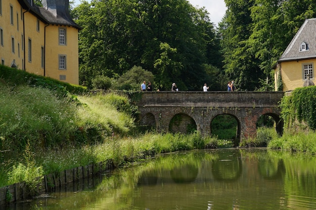 Ponte di pietra che attraversa parte di un fossato d'acqua che circonda il castello di Schloss Dyck Juechen Germania