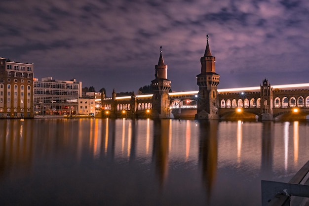 Ponte oberbaum illuminato sul fiume Spree contro un cielo nuvoloso