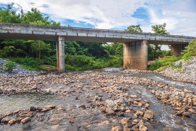 Ponte sul fiume che sgorga dalla diga una diga che utilizza grosse pietre per rallentare il flusso dell'acqua