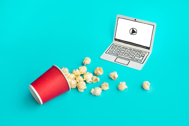 Pop corn con laptop paper art su sfondo color pastello.Cibo e snack, intrattenimento in streaming live.concetti idee.Stile minimale