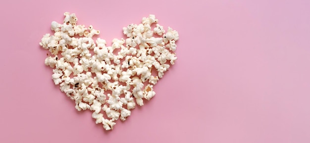 Pop corn cuore su sfondo rosa giorno di San Valentino presente concetto di cinema vista superiore piatto con