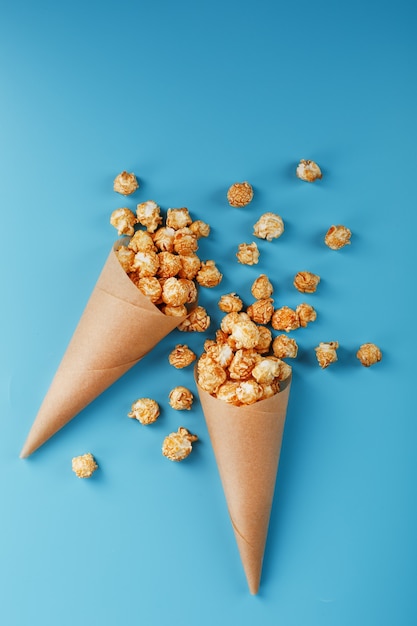 Popcorn al caramello in una busta di carta su uno sfondo blu.