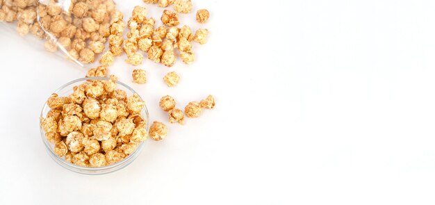 Popcorn al caramello in una ciotola di vetro trasparente con copia spazio su uno sfondo bianco