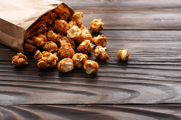 Popcorn caramellato in sacchetto di carta sul tavolo da cucina in legno