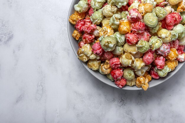 Popcorn colorati fatti in casa sul tavolo di marmo con luce ad alto contrasto. Concetto di snack