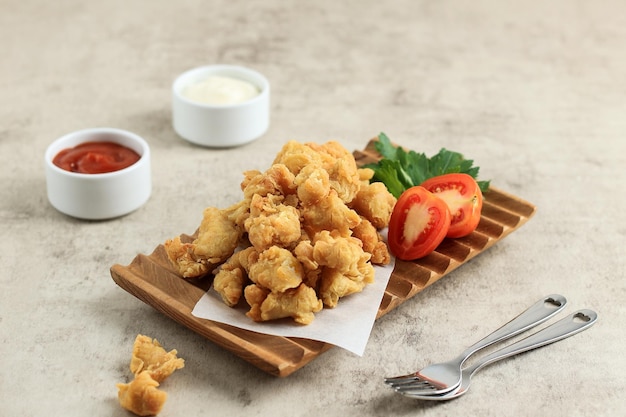 Popcorn di pollo croccante con salsa piccante e maionese servito su piatto di legno