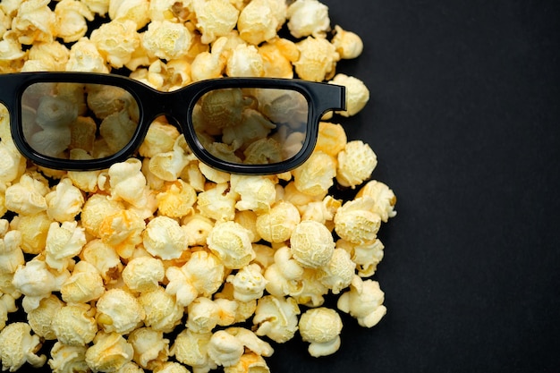 Popcorn e bicchieri per guardare film in formato 3d su sfondo nero. Tema del cinema, sfondo con posto per il testo.