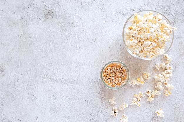 Popcorn e chicchi di mais su sfondo grigio