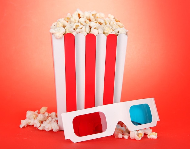 Popcorn e occhiali 3D su sfondo rosso