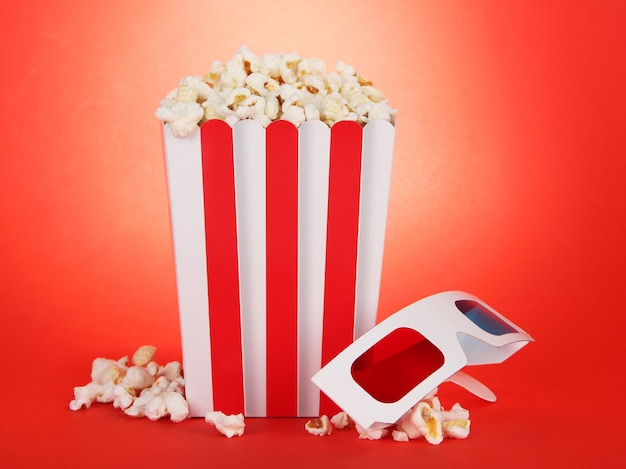 Popcorn e occhiali 3D su sfondo rosso