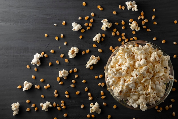 Popcorn e popcorn in una ciotola sdraiata sul tavolo nero vintage