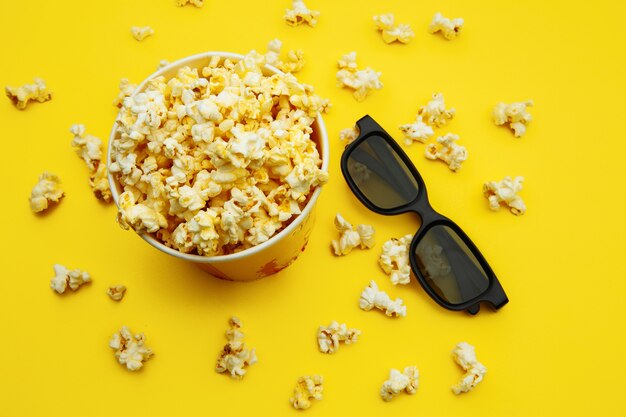 Popcorn in una ciotola e occhiali 3d su colore giallo