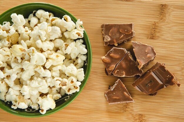 Popcorn in una ciotola e pezzi di barretta di cioccolato con noci e uvetta