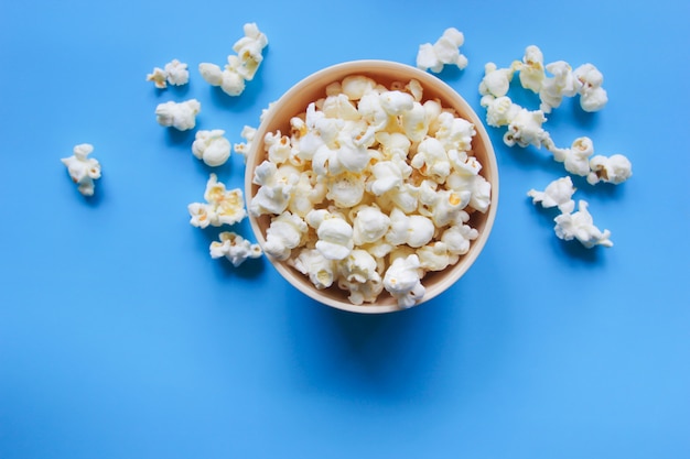 Popcorn in una ciotola sulla tavola blu.