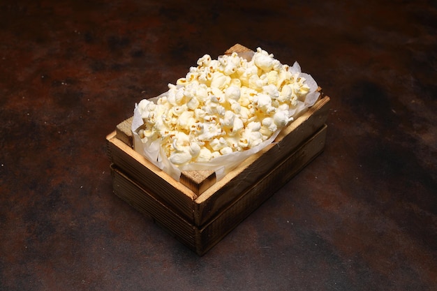popcorn in una piccola cassa di legno isolata su sfondo scuro