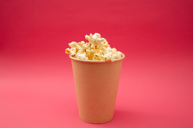 Popcorn in una tazza su uno sfondo rosa brillante