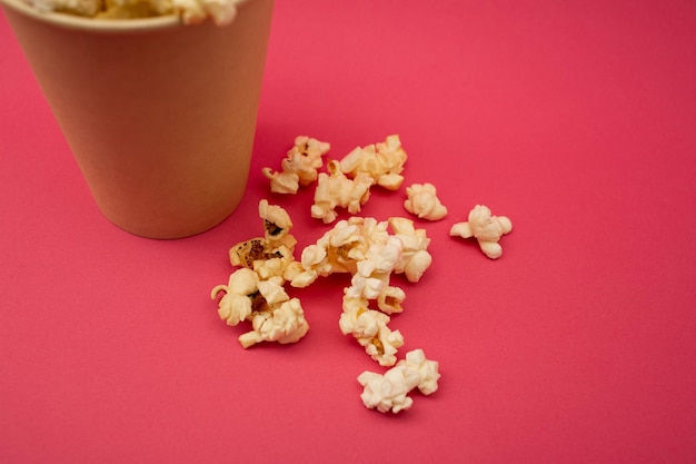 Popcorn in una tazza su uno sfondo rosa brillante