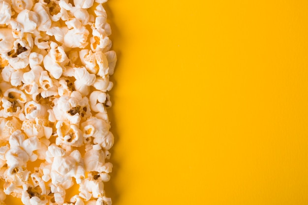 Popcorn piatto laici su sfondo giallo con spazio di copia