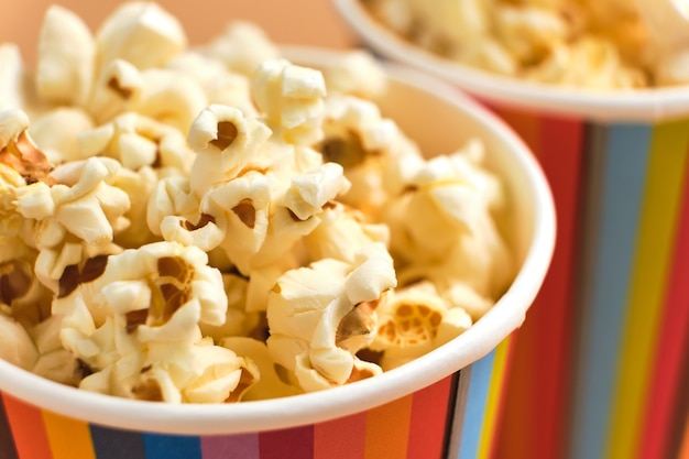 Popcorn salati in bicchieri di carta su una superficie beige