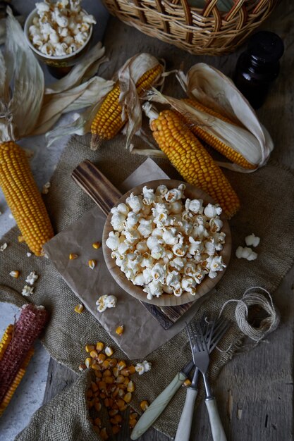 Popcorn tradizionale in una ciotola di legno e pannocchie sul tavolo.